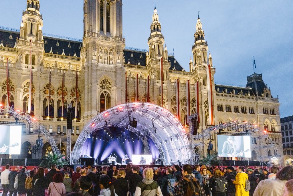 Studio Wey Große Bühne vor dem Wiener Rathaus bei Dämmerung mit einer Menschenmenge