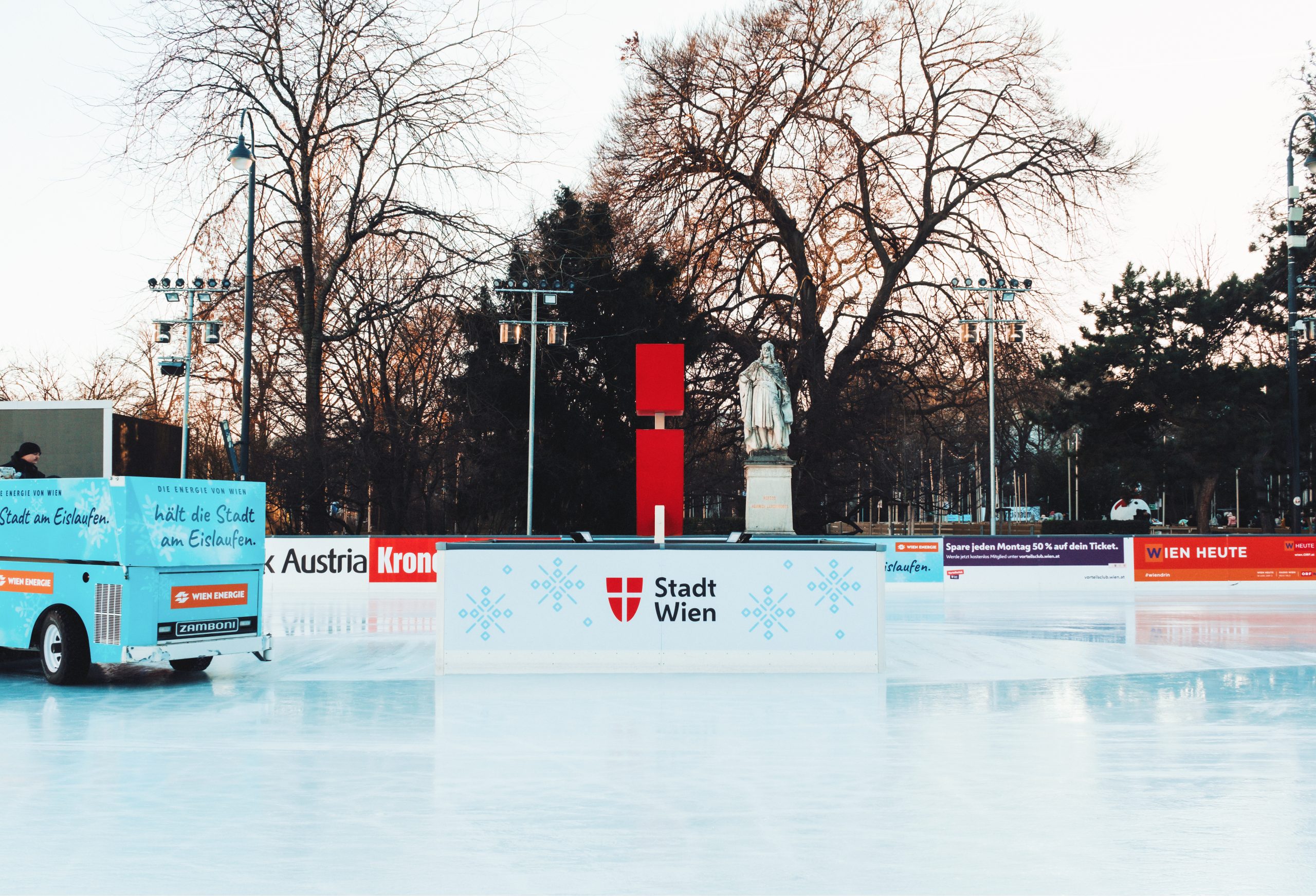 © stadt wien marketing / Florian Ankerl Foto des Stadt Wien Wappens auf einem Podest auf der Eisfläche. Links ist eine Eisreinigungsmaschine.