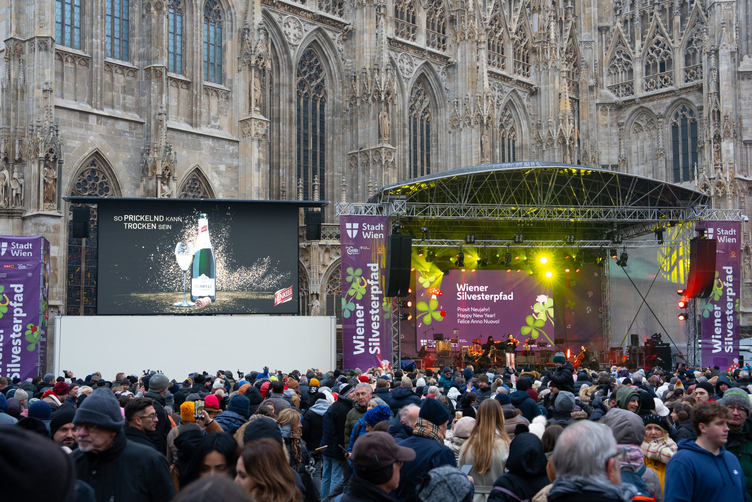© stadt wien marketing / Christian Kremser Bühne vor dem Wiener Stephansdom mit einer großen Leinwand links daneben und großer Menschenmenge beim Silvesterpfad 2024.