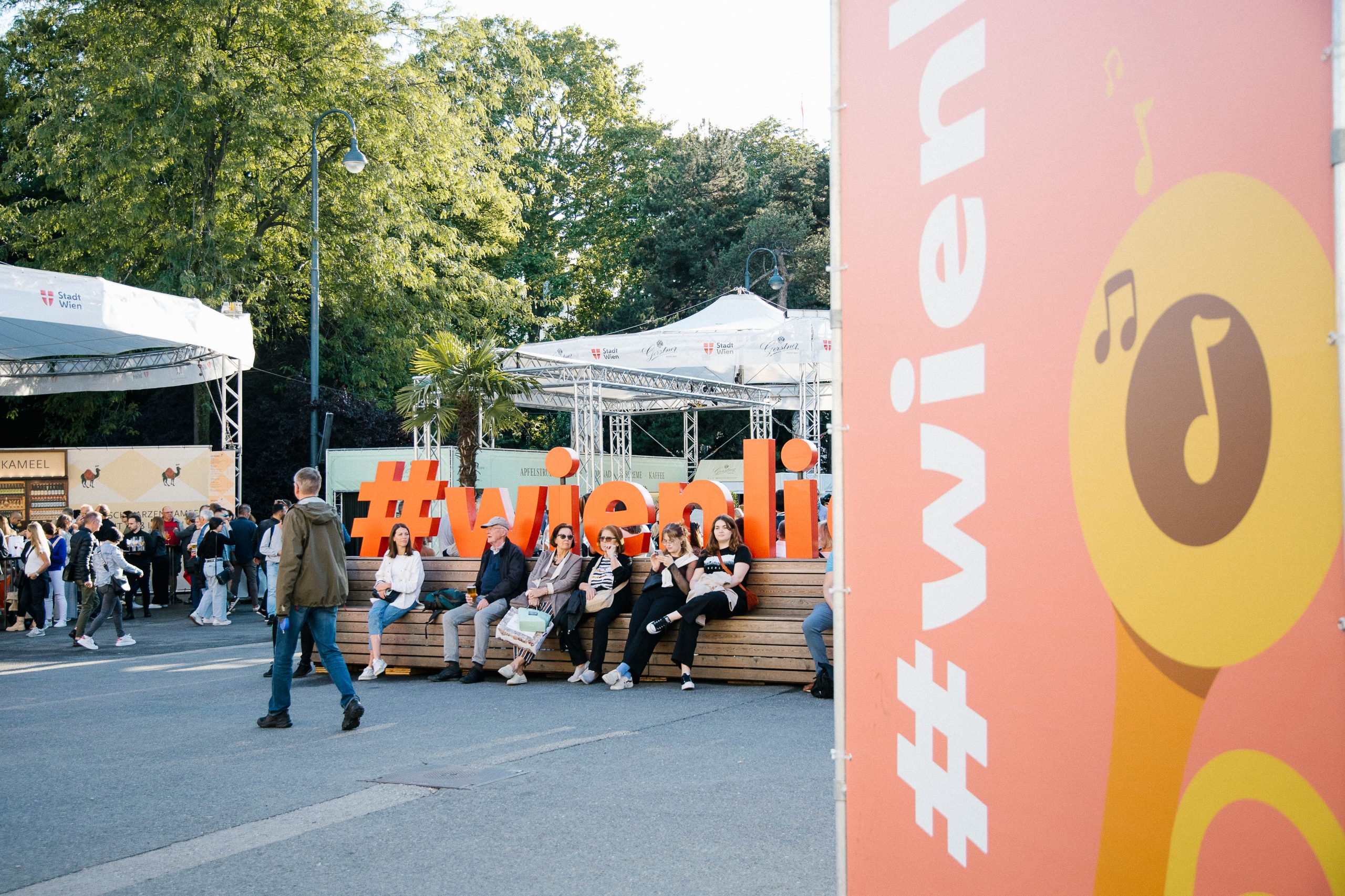 © stadt wien marketing / Studio Wey Aufnahme einer Bank mit dem Schriftzug "Wienliebe". Auf der Bank sitzen Menschen.