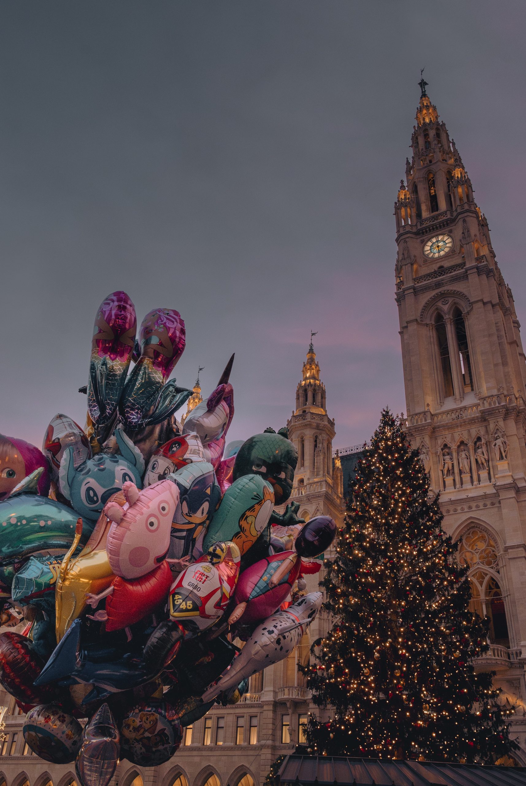 Sicht auf den Rathausturm und dem Christbaum vor dem Rathaus. Links befinden sich viele Heliumluftballone im Bild.