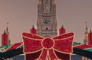 Teil eines aufgesplitteten Fotos des Rathaus. Auf diesem ist der Mittelturm zu sehen sowie die Masche des großen Eingangsbogen. Der Himmel ist rosa gefärbt.