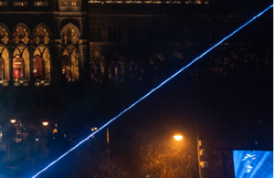 Teil eines aufgesplitteten Fotos des Rathaus. Auf diesem ist die rechte Seite des Rathaus bei Nacht zusehen. Das Rathaus ist erleuchtet und es sind Laser zu sehen.