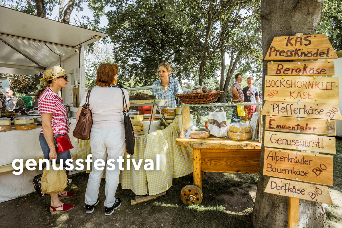 3 Personen vor einem Marktstand beim Genussfestival im Stadtpark.