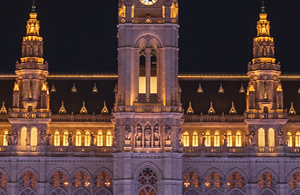 Teil eines aufgesplitteten Fotos des Rathaus. Auf diesem ist die Turmmitte und das Dach zu sehen. Das Rathaus ist beleuchtet.